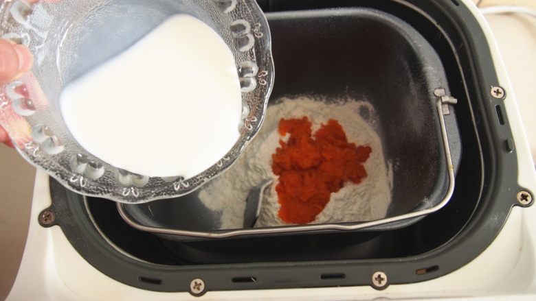 三色吐司,将面粉放入面包机桶中，在角落里放入酵母。加入胡萝卜泥，将糖和盐融化于牛奶中加入，开启揉面程序揉成光滑面团。