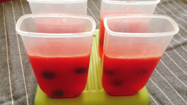 西瓜冰棍,将放过蓝莓的西瓜汁模具放入冰箱冷冻层，冻1个小时左右，此时西瓜汁稍稍凝固