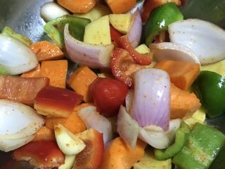 三汁焖鸡翅,将土豆、胡萝卜、红青椒、洋葱、蒜放入一个平底锅里，用辣椒面、盐、油（比平时炒菜的量多些）搅拌均匀。
