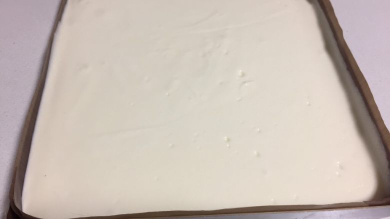 可可旋风瑞士卷（后蛋法）,金盘里铺上油纸或油布，把三分之二的蛋白霜缓缓倒进金盘，抹平表面放置一边。