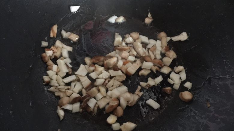鸡腿包饭,锅里热油后放入香菇和杏鲍菇粒炒至干香