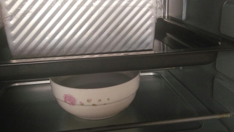 金砖土司,烤箱底部放一碗热开水，土司模具连同烤盘一起放入烤箱，进行二次发酵。