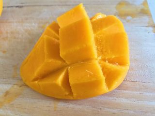 芒果牛奶布丁,将芒果皮翻起后用刀沿皮切下即可切成丁