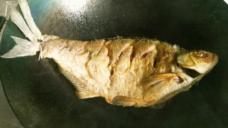 红烧武昌鱼,小心翻面了，将另面也煎至金黄色。 注意啦，不要去动鱼，转动锅身，让鱼受热均匀。