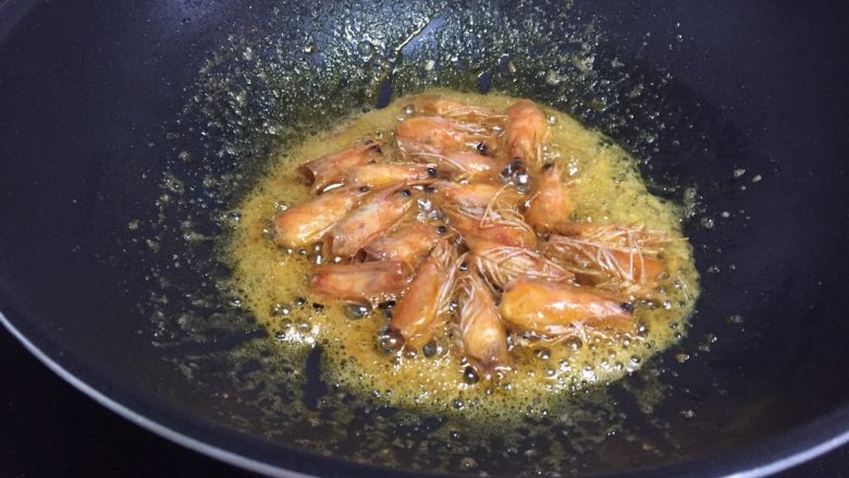 鲜虾豆腐煲,接着来处理虾头，锅中倒入适量油，烧热下虾头，虾出虾油，炸至虾头金黄，如图，关火，夹出虾头，留虾油在锅中