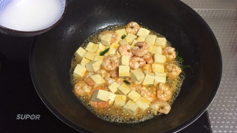 鲜虾豆腐煲,倒入调好的水淀粉，翻炒均匀至汤汁浓稠，撒盐，炒匀即可