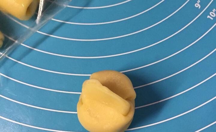 蛋黄酥（黄油版）,手指中间按一下，两头捏起压扁。把豆沙蛋黄馅放在中间裹起来，包圆！