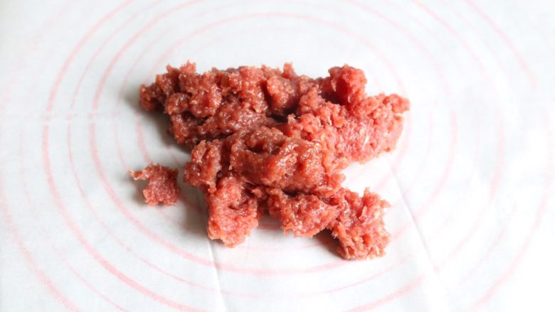 自制蜜汁猪肉脯,腌制好的肉取1/2在油纸上。