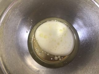 网红肉松小贝,玉米油跟牛奶倒入盆中搅拌乳化，乳化好的玉米油牛奶是有点浓稠的，