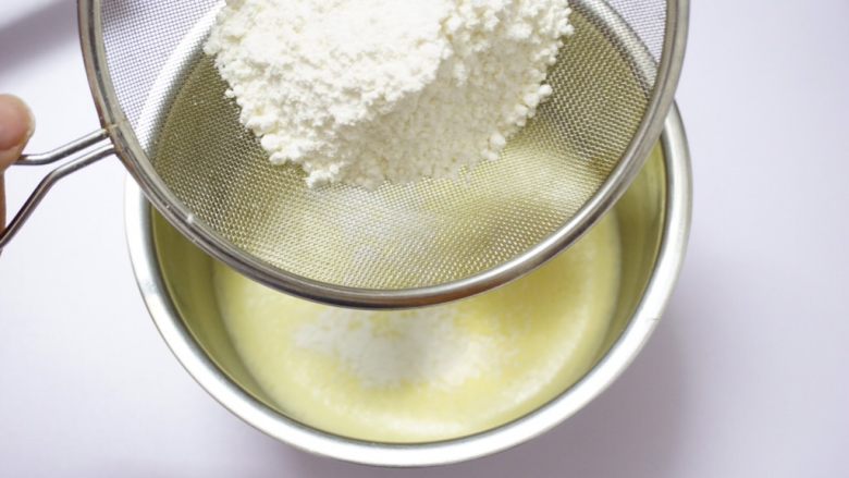 基础戚风蛋糕（两蛋配方）,将低粉过筛，离蛋液上空20厘米处，筛入乳化好的蛋黄液里面。