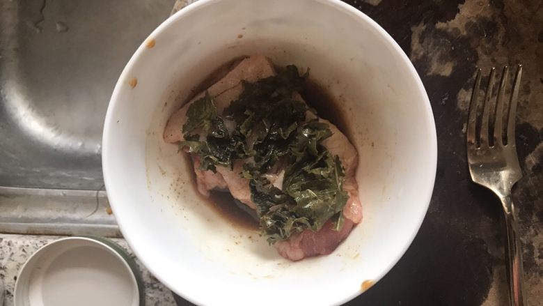 茶香猪颈肉,猪颈肉放入碗中，抓匀调料，铺上一层绿茶叶，腌制一晚