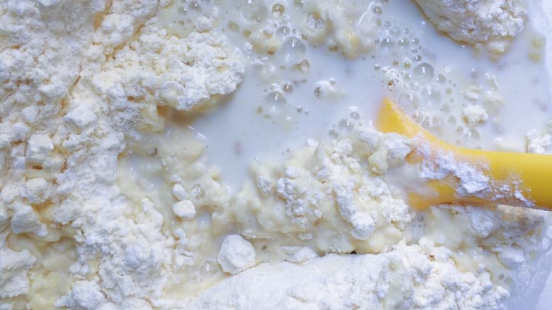 奶香玉米窝窝头,将搅拌均匀的配方奶倒入面粉中先用刮刀进行搅拌均匀