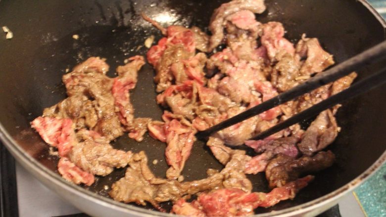 橙汁芝麻牛肉,炒锅热锅后，加入两大匙油。油热后，分次放入牛肉片，入锅后迅速用筷子拨散，以免牛肉黏成一团。 