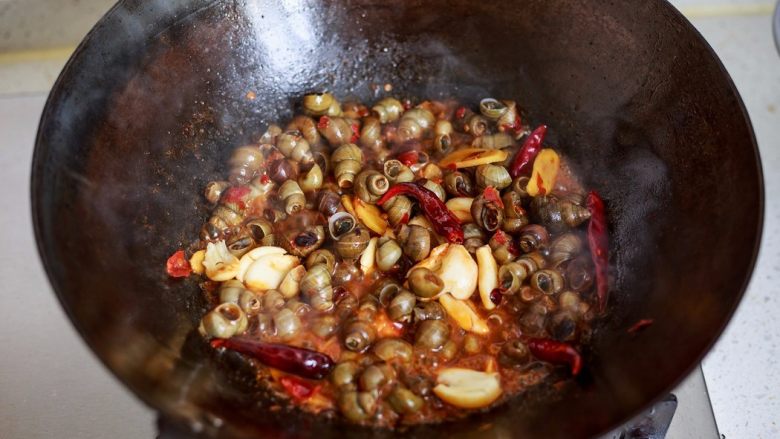 香辣螺蛳,煮到锅里水减少后，撒上蒜瓣大火翻炒收汁。