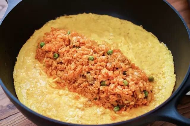 治愈系蛋包饭,关火，米饭放在蛋皮中间，翻起蛋皮的一边将米饭包住，把锅倾斜后翻扣在盘中