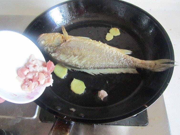 毛豆烧黄鱼, 将姜片和五花肉丁放在鱼边上先煸炒一下；