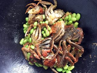 六月黄炒年糕,把洗净的毛豆子入锅一同翻炒5分钟，螃蟹壳变红。