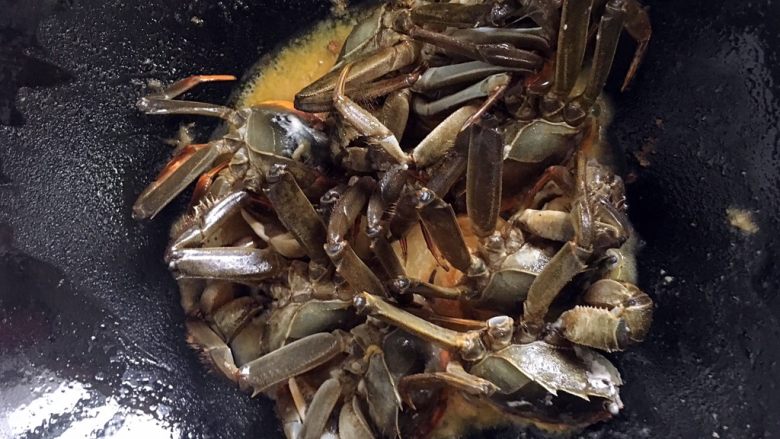 六月黄炒年糕,中火加热后的油锅，此时把螃蟹切面整齐码入锅内，煎两分钟。