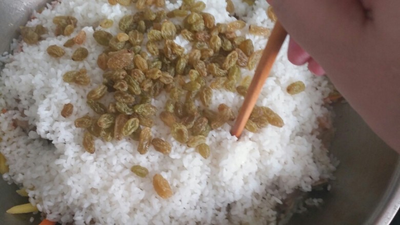 新疆羊排抓饭,倒入米讲葡萄干撒到上面，用筷子到几个洞，然后盖上锅盖焖十五分钟。