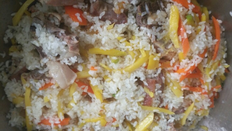 新疆羊排抓饭,打开翻一下，将刚才炒胡萝卜和黄萝卜倒出的黄色汤延锅边倒入，量根据米得多少自己控制。继续盖上锅盖焖15分钟。