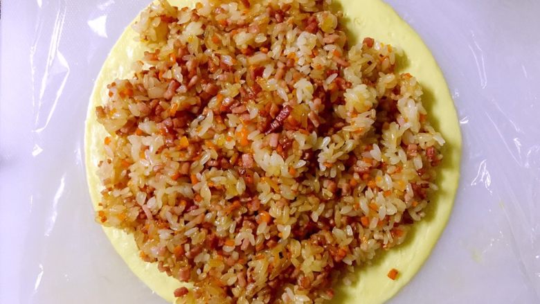 培根胡萝卜鸡蛋卷饭团,将炒好的米饭铺在蛋皮上