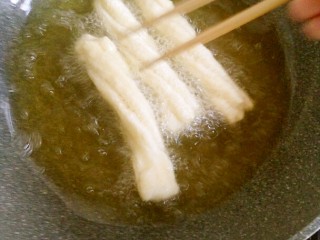 家庭自制油条,用筷子翻拨，使其受热均匀。
