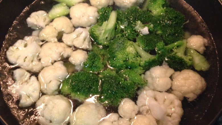 焗烤花椰菜（西兰花）,将处理好的花椰菜和西蓝花放入加了盐和少许沙拉油的滚水中煮3-4分钟。