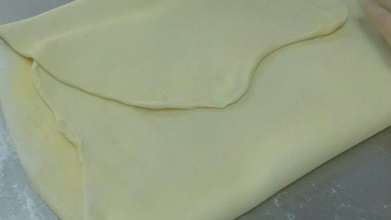 红豆丹麦包,将面团两边对折包住奶油，趁面团还没完解冻