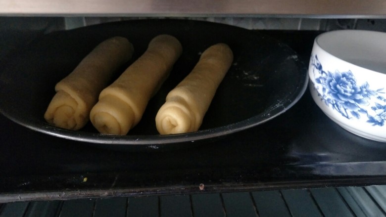 毛毛虫面包,三个全部卷好之后放入烤箱进行二次发酵，旁边放一碗热开水，防止水分蒸发过快，表皮变硬，二次发酵约40分钟