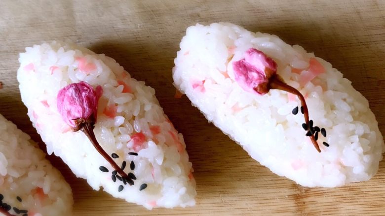 日式手鞠壽司飯團,快速將米飯捏成所需形狀，放一朵櫻花和芝麻做裝飾。