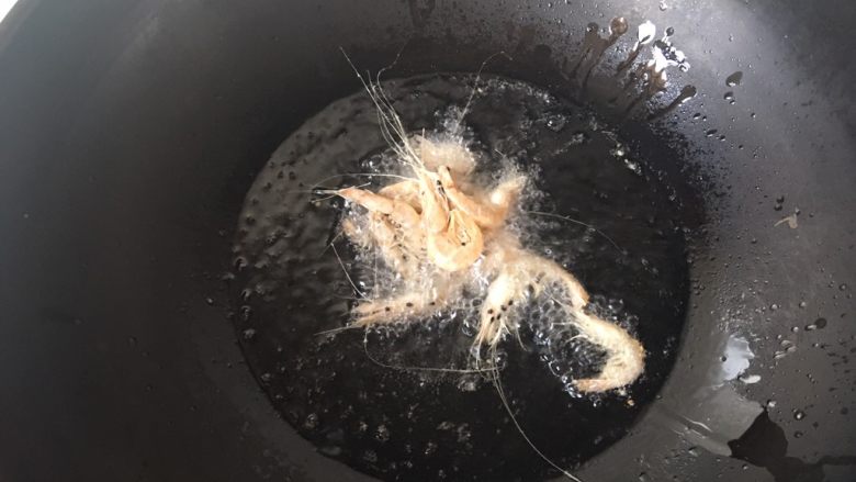 香酥小白虾,锅中放入比炒菜多些的油，烧到六成热，可以先少放几个虾试油温，图中这个状态就可以