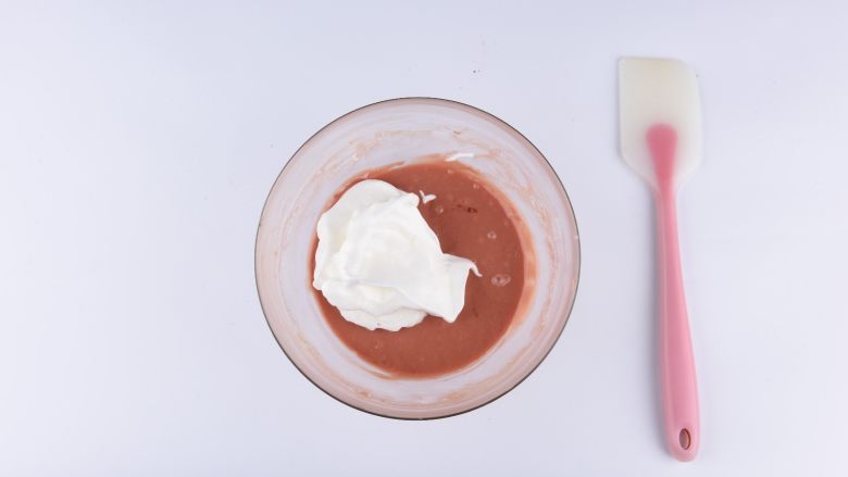 草莓花式蛋糕卷,取三分之一打发的蛋白部分到蛋黄部分用硅胶刮刀快速翻拌的手法拌均匀