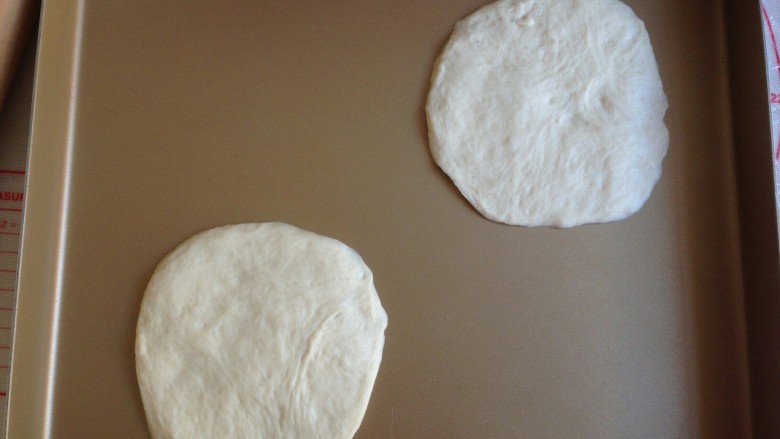 脆皮肠面包袋,发酵好的面团排气，分成16克左右一个小面团，盖保鲜膜，醒发15分钟，然后将小面团擀成圆形，移到不沾烤盘上。