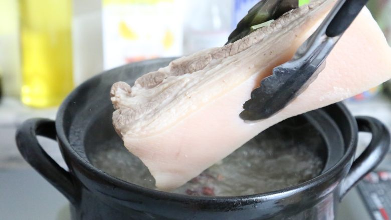 传统秘制 梅干菜扣肉,将肉捞起来，冲去表面的浮沫。