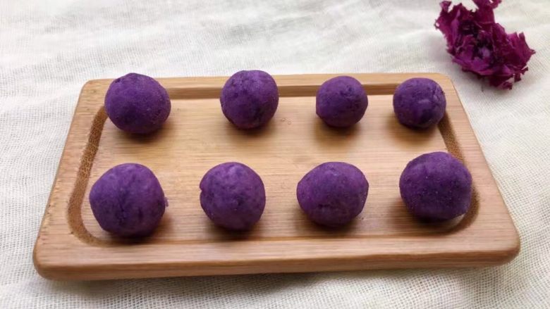 紫薯南瓜椰蓉球,将紫薯面团搓成长条，用刀切小块，再搓成大小一致的小圆球。