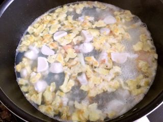 海鲜豆腐煲,接着倒入蒜末，虾，瑶柱，海米和鱼丸一起翻炒，炒香以后倒入2碗清水，下葱白，大火煮开以后，调小火煮5分钟。