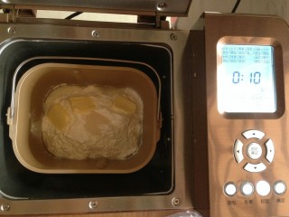 花辫豆沙面包,加入面包粉，在面包粉上面加入切成小块的黄油和酵母，再将面包桶放入到面包机内，选择和面十分钟。