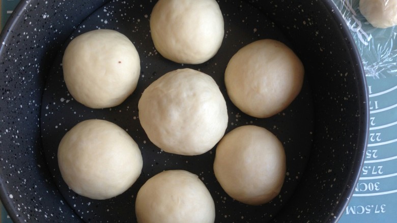 花辫豆沙面包,收口朝下，50克的面团包入50克的豆沙馅，将做好的面包胚放入到八寸圆形不粘模里，大的面包胚放中间，每个都留有空隙，如图摆放。