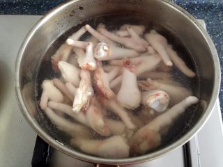 酱醋泡鸡爪,锅里放入清水和几片姜片烧开，放入切好的鸡脚。