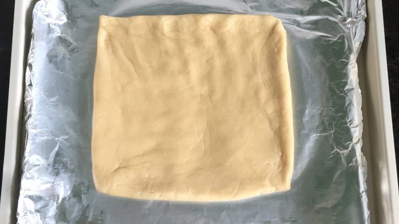 燕麦瓜子仁酥块,将面团放在铺了锡纸的烤盘里，借助刮板整型成一个方形，厚度1厘米左右；
