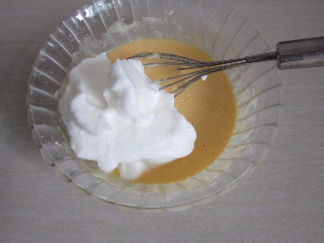 蔓越莓蛋糕卷,取三分之一蛋白糊，倒进蛋黄糊中，用翻拌的手法混合均匀。