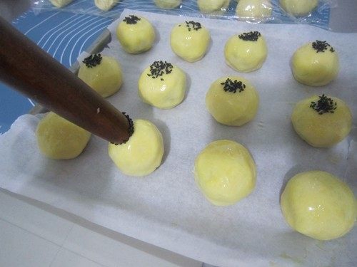咬一口酥软掉渣的蛋黄酥,用擀面杖头在每个蛋黄酥饼胚顶粘上黑芝麻