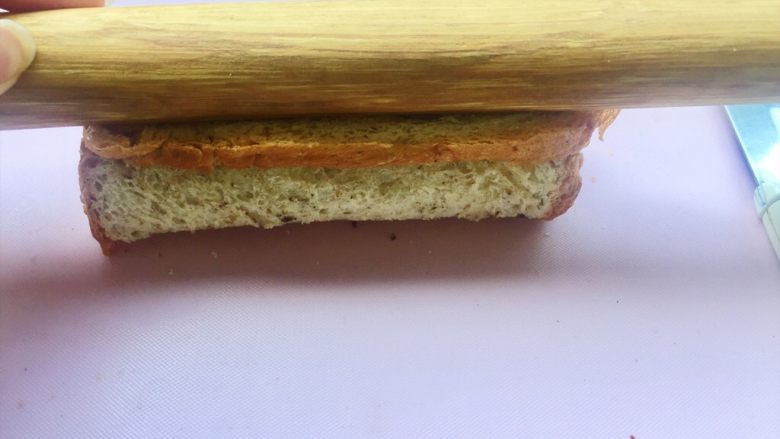 #快手早餐# 香蕉吐司卷,再用擀面杖压平，为了防止香蕉和面包中间有空隙，不好看