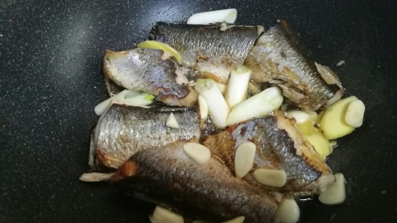 红烧鲭鱼,一面煎好后翻面，中小火煎到两面金黄。放入葱姜蒜。