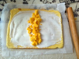 ＃樱桃图案＃纹身蛋糕卷,蛋糕放凉之后，铺上酸奶和芒果粒，借助擀面杖将蛋糕卷