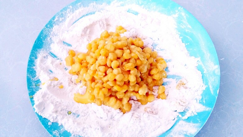 香酥玉米粒,玉米粒倒入面粉中。