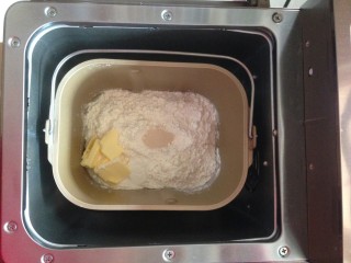 可爱小熊面包,加入切成小块的黄油，在面粉最顶端加入酵母。将面包桶放入到面包机内。