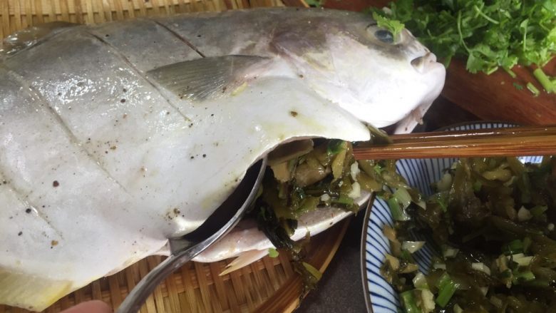 酸菜红烧金鲳鱼,用几汤匙刚炒好的酸菜塞入鱼肚鱼头内部。