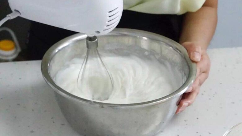 人人都可以做的戚风纸杯蛋糕,将白糖加入鸡蛋蛋白中，用电动动打蛋器打发。