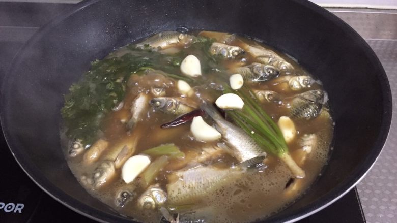 酥焖鲫鱼,放蒜，撒盐，继续小火炖20分钟